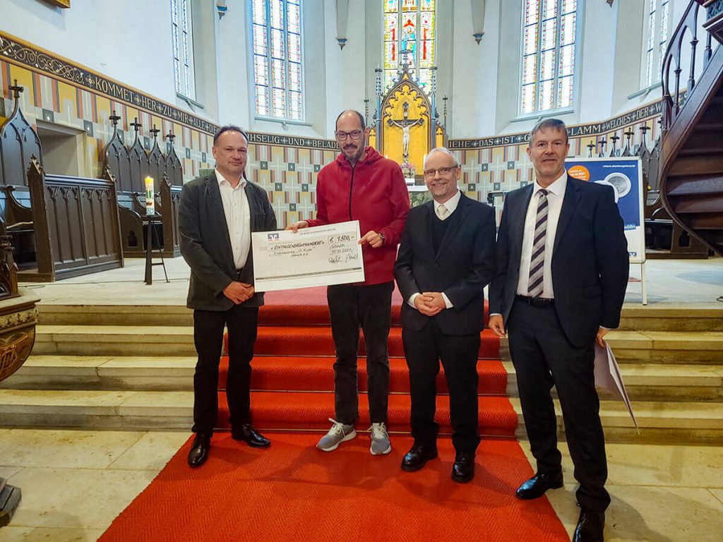 Raik Romisch (links) und Holger Scmidt (rechts) übergeben an den Vorsitzenden des Kirchbauvereins Schmölln, Dr. Jörg Milde, einen Scheck der VR-Bank Altenburger Land über 1500 Euro.